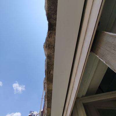 קיר אבן עם לוח מתכת לבן מתחת לשמיים כחולים