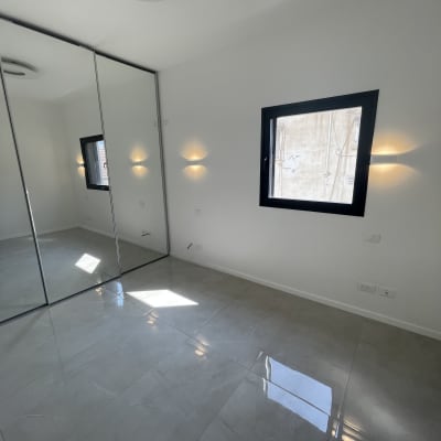 חדר עם קירות לבנים ורצפת אריחים אפורה