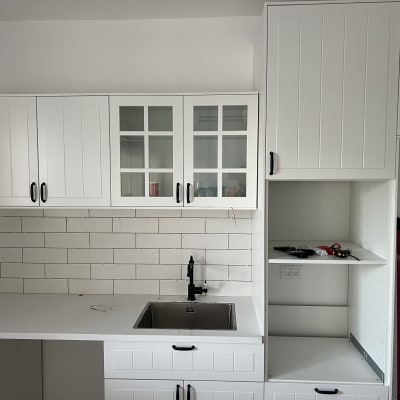 ארונות מטבח לבנים עם ידיות שחורות וכיור נירוסטה