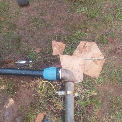 צינור פלסטיק עם מחבר מתכת על אדמה רטובה