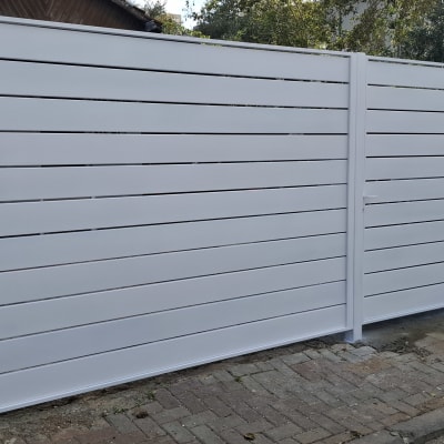 שער מתכת לבן ליד גדר ישנה