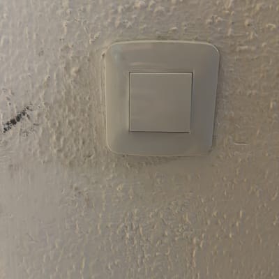 מתג חשמל לבן על קיר מחוספס