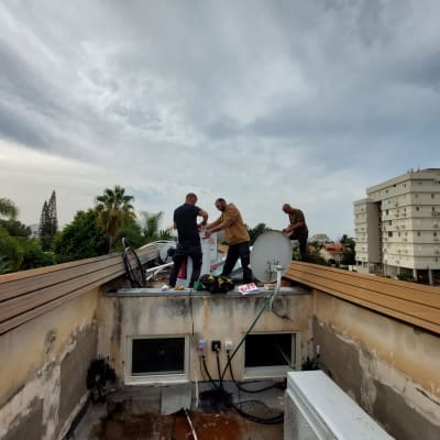 אנשים עובדים על דוד שמש על גג בניין