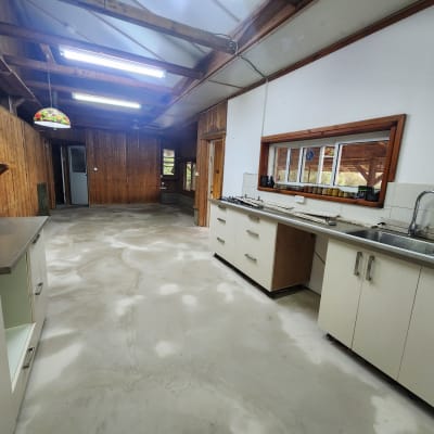 מטבח עם רצפת בטון חשופה, ארונות לבנים וכיור נירוסטה