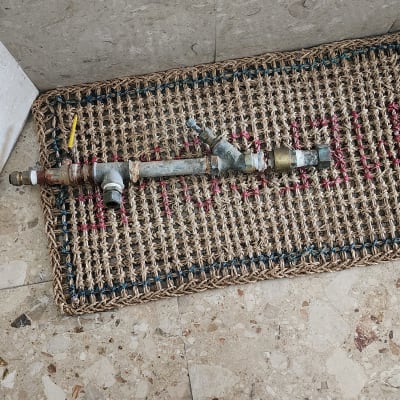 צינור מתכת עם מחברים וברז על שטיח