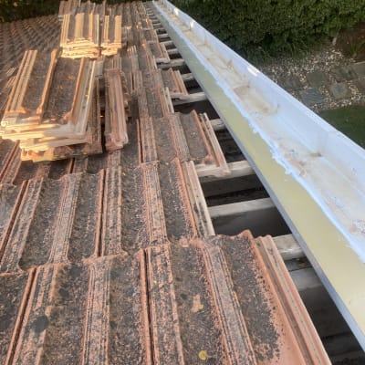 רעפים מונחים על גג עם תעלה לבנה בצד