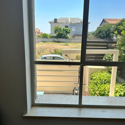 חלון זכוכית עם נוף חיצוני של גינה ובתים