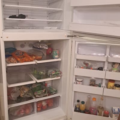 מקרר פתוח עם מדפים ריקים ומוצרים שונים