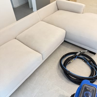 ספה בהירה עם מכונת ניקוי וציוד ניקוי