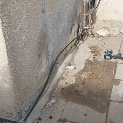 צינורות מים וכלי עבודה על רצפה ליד קיר