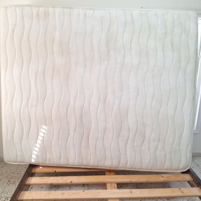 מזרן עומד על מסגרת מיטה בחדר מואר