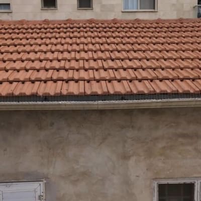 גג רעפים אדום עם קיר בניין ברקע