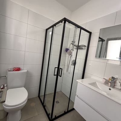 מקלחון זכוכית עם דלתות שחורות ומדף מתכת