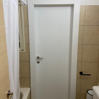 דלת לבנה עם ידית מתכת בחדר אמבטיה