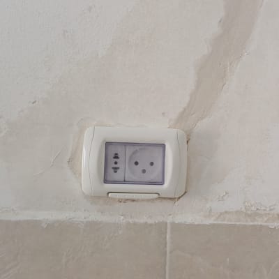שקע חשמל בקיר עם טיח מתקלף