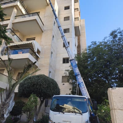 משאית עם מנוף ליד בניין מגורים גבוה