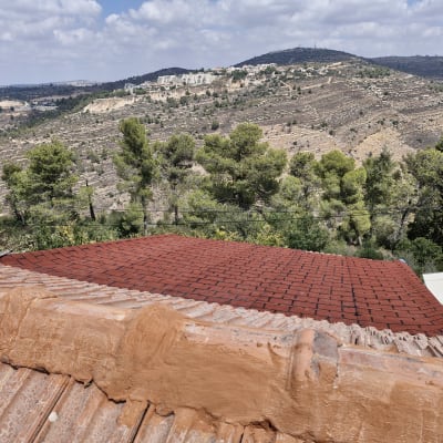 גג רעפים אדום עם נוף הררי ברקע