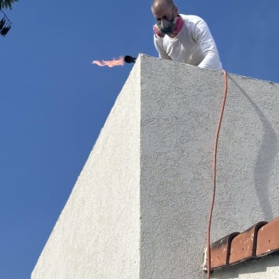 אדם עובד על איטום גג עם מבער