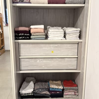 בגדים מקופלים בארון עץ עם מדפים ומגירות