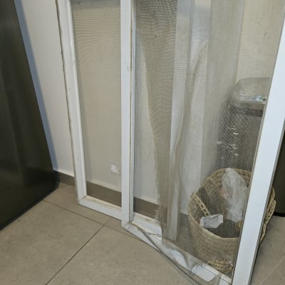 מסגרות חלונות עם רשתות קרועות על הרצפה