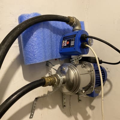 משאבה כחולה מותקנת על קיר עם צינורות מחוברים