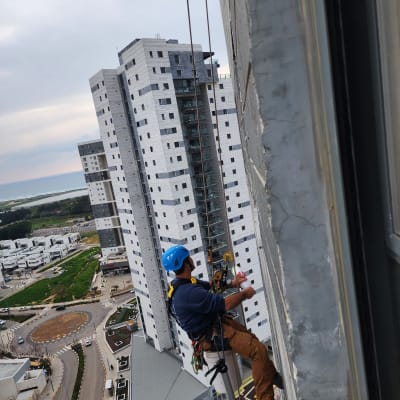 אדם עם קסדה כחולה עובד על חבלים בגובה