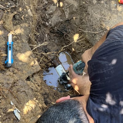 אדם מתקן צינור מים באדמה עם כלי עבודה