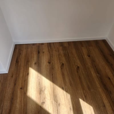 רצפת פרקט עץ כהה בחדר עם קירות לבנים