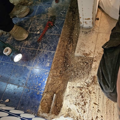 כלי עבודה על רצפה כחולה, חפירה ליד צינור חשוף