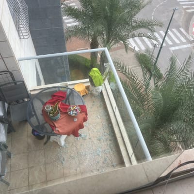 מרפסת עם שולחן זכוכית ושברי זכוכית על הרצפה