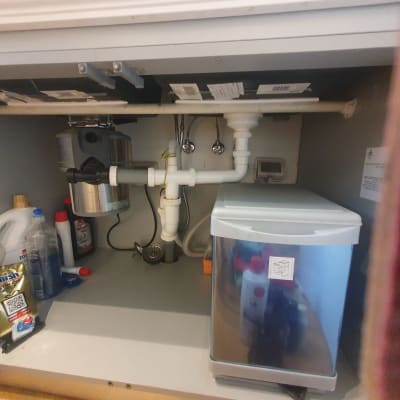 כיור עם צנרת וכלים מתחת לארון מטבח