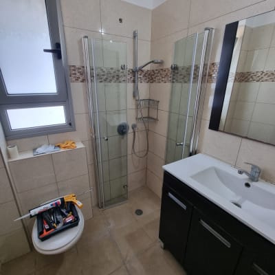 מקלחון עם כלים על האסלה וחלון בצד