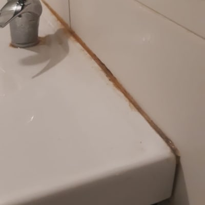 ברז וכיור עם סימני חלודה על האריחים