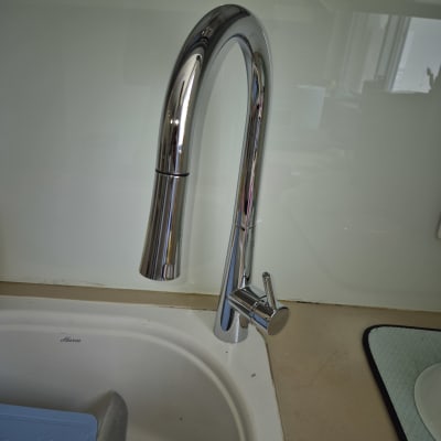 ברז נירוסטה מעל כיור מטבח עם כלים