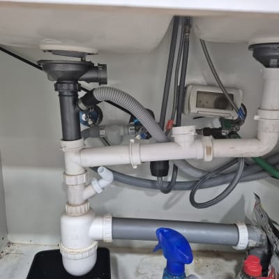 צנרת מתחת לכיור עם חיבורים וצינורות שונים