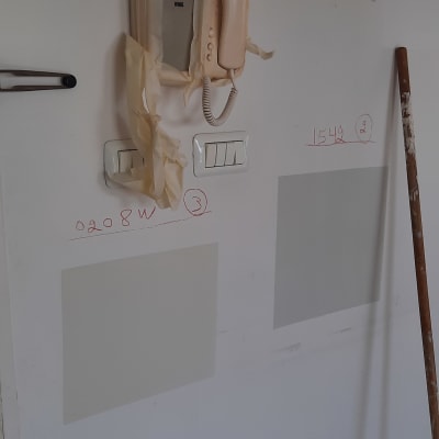 קיר עם אינטרקום מכוסה בנייר דבק, דגימות צבע, ומתגים