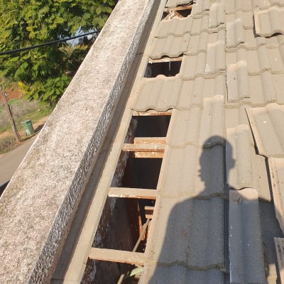 רעפים שבורים על גג עם צל של אדם