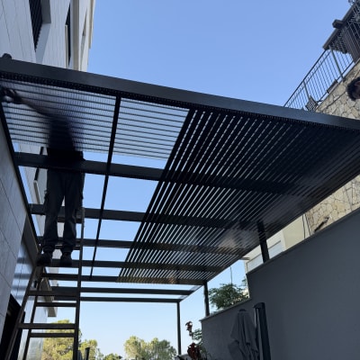שני אנשים מתקינים פרגולה מאלומיניום בחצר