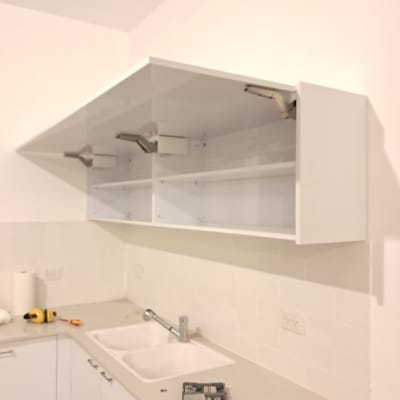 ארונות מטבח לבנים עם כיור וכלים על השיש