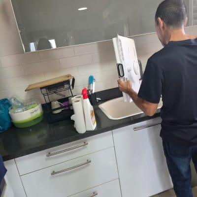 אדם עובד על חלק של מקרר במטבח