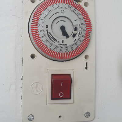 טיימר חשמלי עם מתג הפעלה על קיר לבן