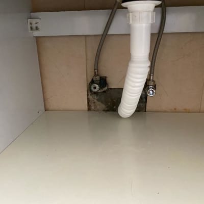 צינור ניקוז לבן מתחת לכיור עם ברזים