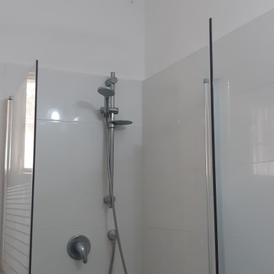 מקלחת חדשה עם אריחים לבנים וברז מודרני