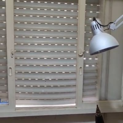 תריסים סגורים עם מנורת שולחן וכלים על שולחן עבודה