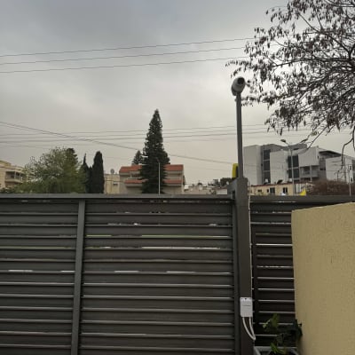 מצלמת אבטחה מותקנת על עמוד ליד גדר מתכת