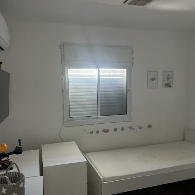 חלון אלומיניום עם תריסים סגורים בחדר שינה