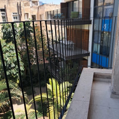 מרפסת עם מעקה ברזל ונוף של בניינים ועצים