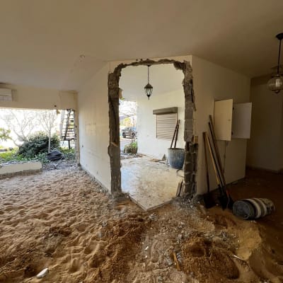 אתר בנייה עם קיר שבור וכלי עבודה על הרצפה