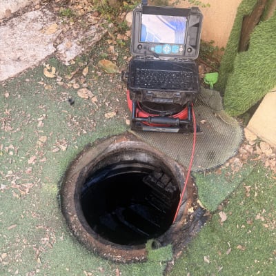 מכשיר בדיקה ליד פתח ביוב עם צינור אדום