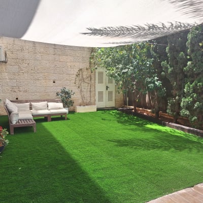 גינה עם דשא סינתטי וצמחים מסביב